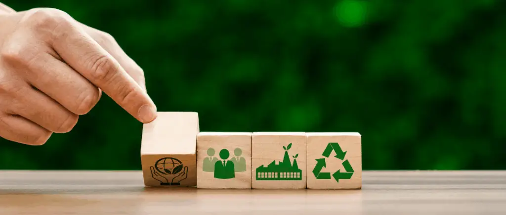 une main en gros plan déplace des cubes en bois sur lesquels apparaissent des icônes de couleur verte qui représentent la transition énergétique