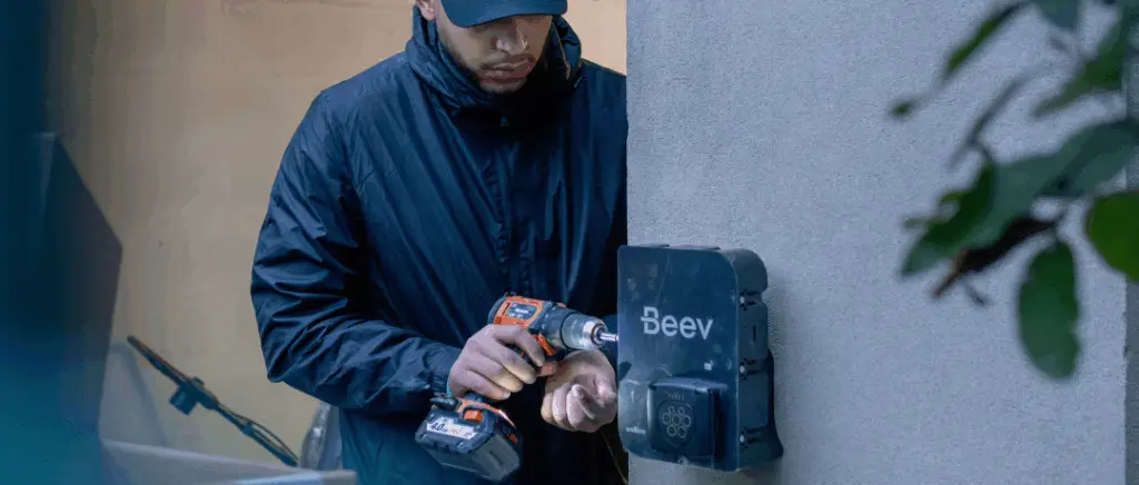 un homme installe une borne de recharge électrique beev
