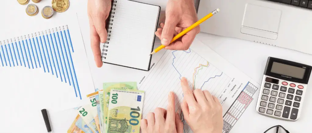 mains vues du dessus en train de noter le montant des aides sur un carnet